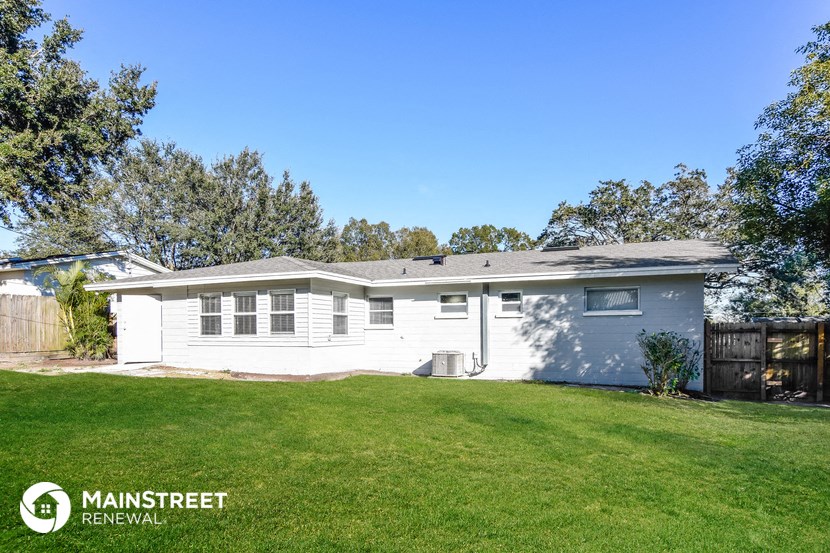 a white house with a green lawn and trees