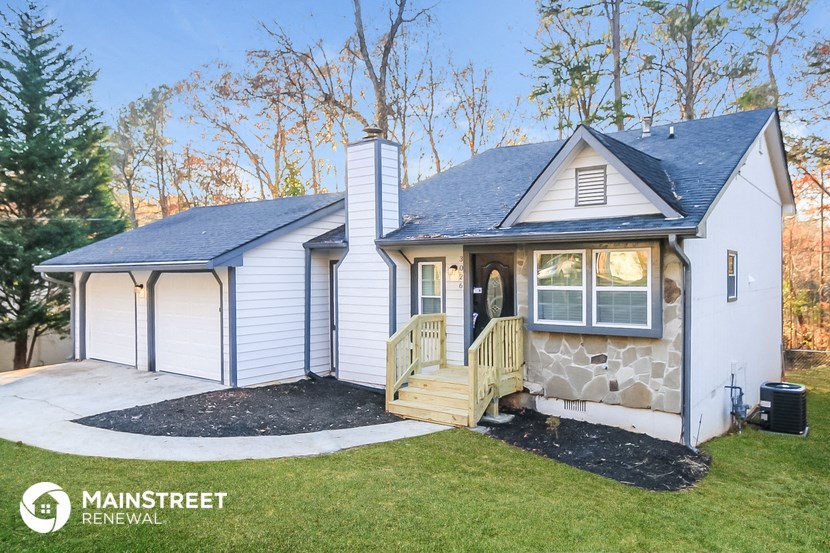 the exterior of a small white house with a porch and a deck