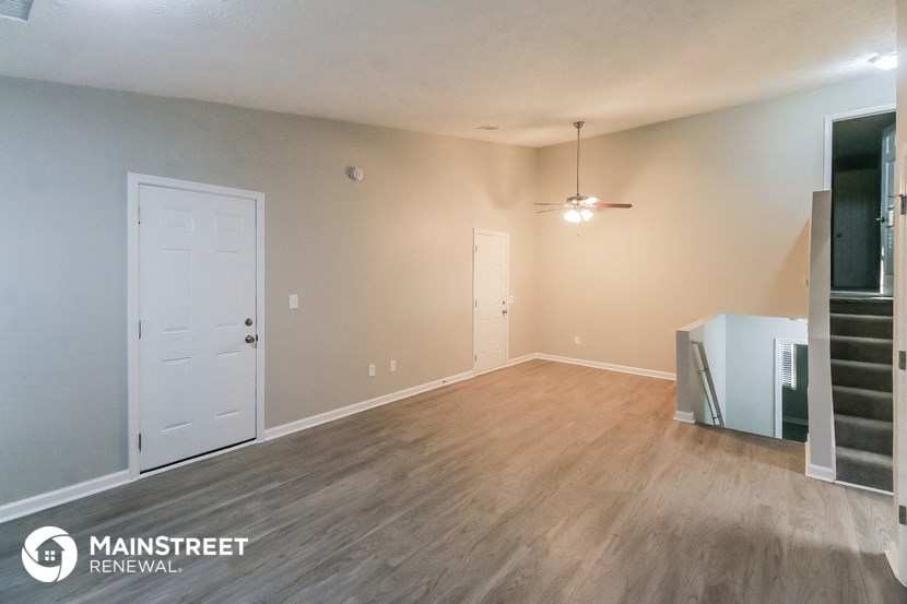 an empty living room with wood flooring and a white door