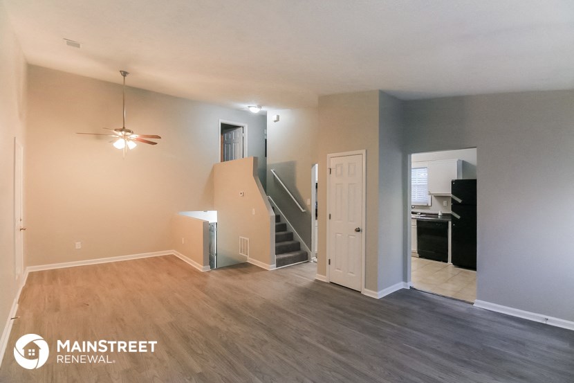 an empty living room with a staircase and a ceiling fan