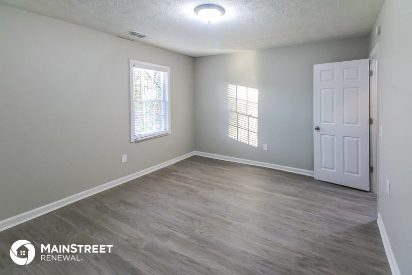 the spacious living room with a white door and wood flooring