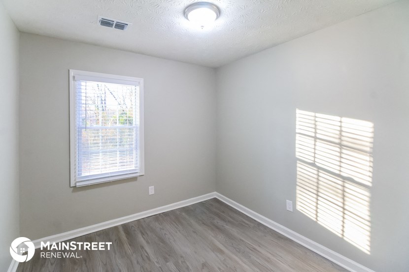 the interior of an empty room with wood flooring and a window