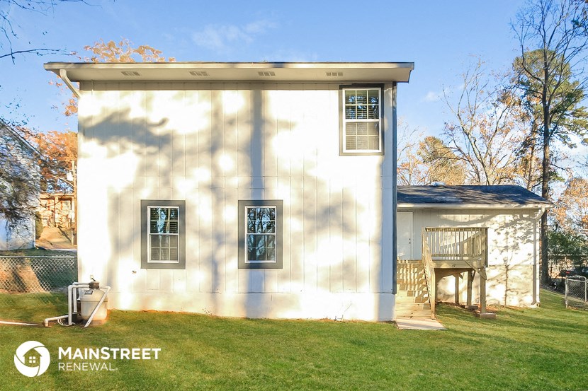 the exterior of a small white house with a yard and a porch