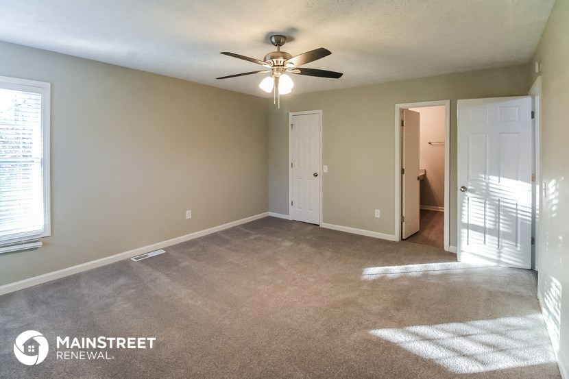 an empty living room with a ceiling fan