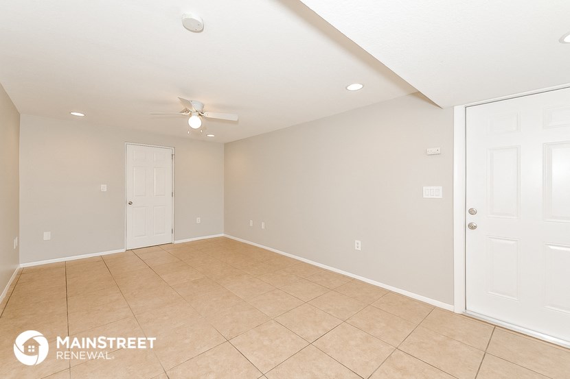 the spacious living room with tile flooring and a ceiling fan
