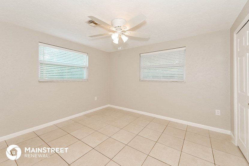 an empty living room with a ceiling fan and a tiled floor