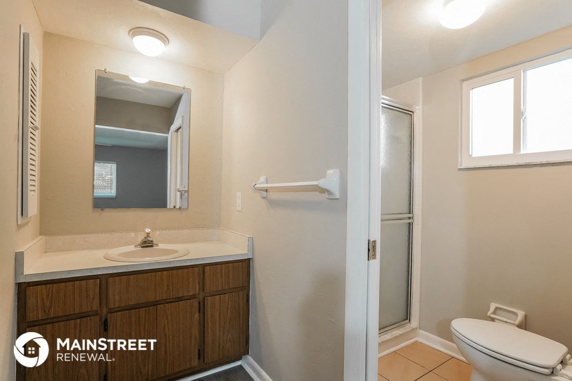 a bathroom with a toilet sink and mirror and a shower