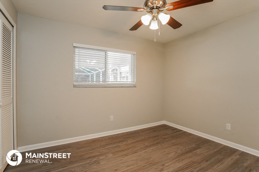 the spacious living room of this manufactured home has a ceiling fan and a window