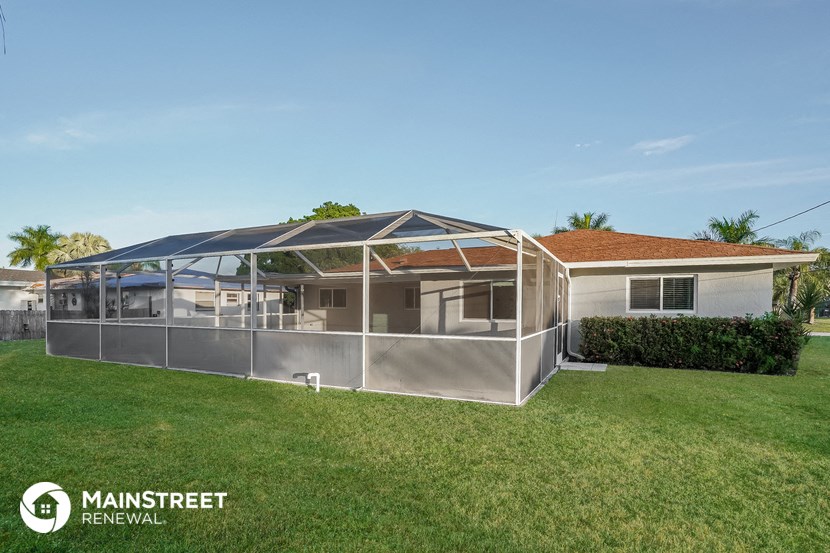 a conservatory with a roof on a lawn in front of a house