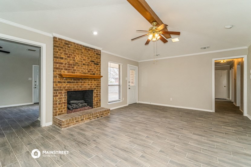 a living room with a brick fireplace and a ceiling fan