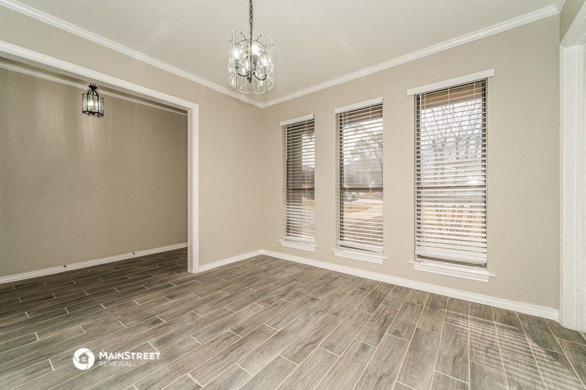 an empty living room with windows and wood flooring