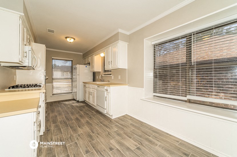 a kitchen with white cabinets and a large window