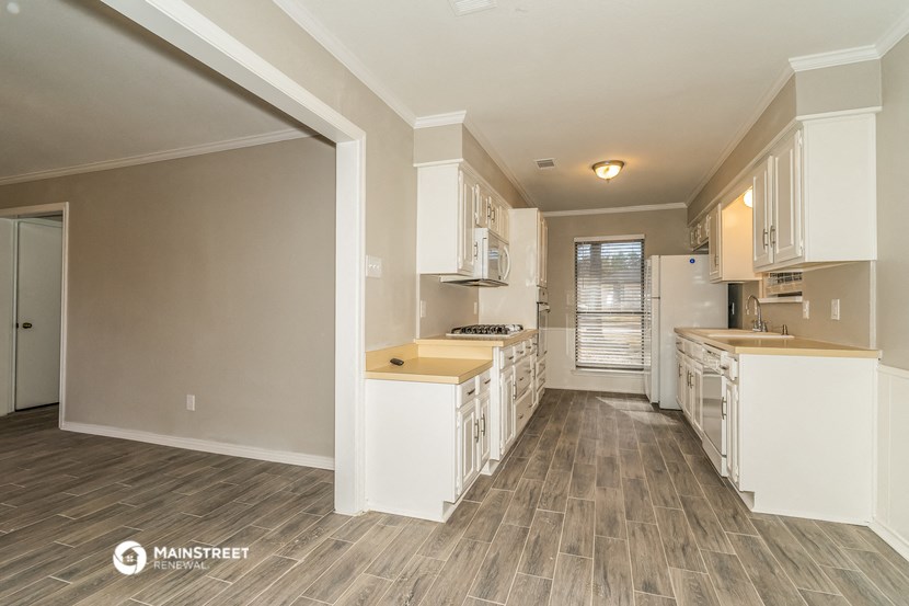 a kitchen with white cabinets and a wood floor
