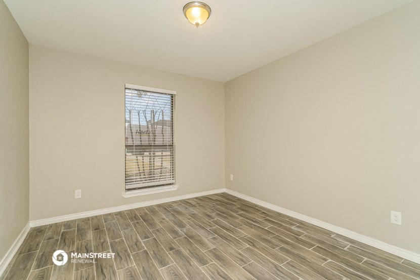 the spacious living room with wood flooring and a window