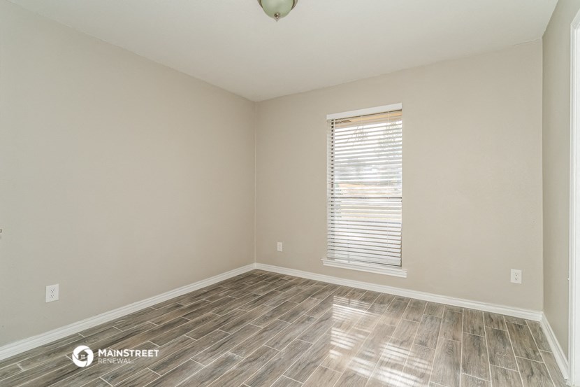 the spacious living room with wood flooring and a window