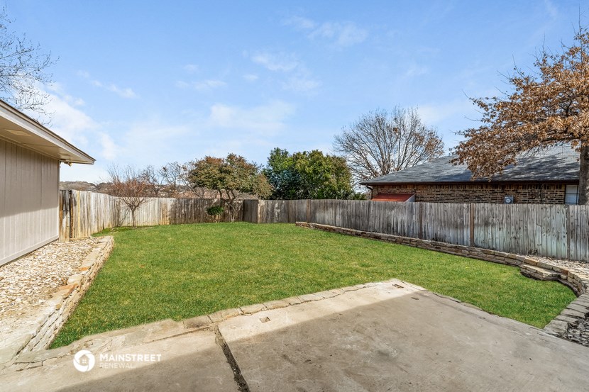 a backyard with a wooden fence and a lawn