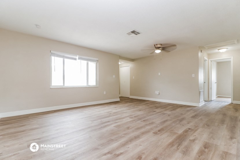 the living room and dining room of an empty house with wood flooring