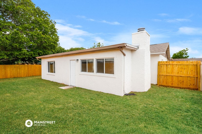 a small white house with a yard and a wooden fence