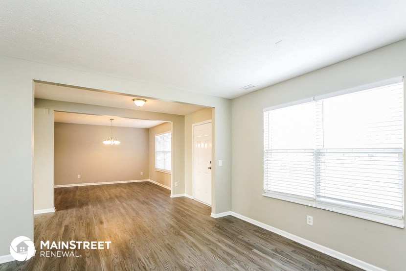 the living room of an apartment with wood flooring and a large window