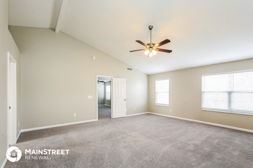 the spacious living room with carpet and ceiling fan