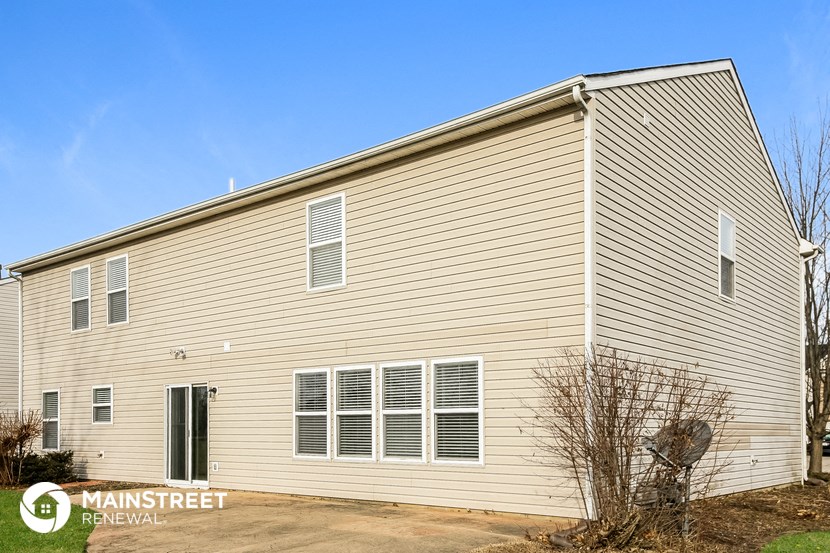 the outside of a house with tan siding and white windows
