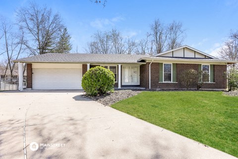 a brick house with a driveway and a lawn