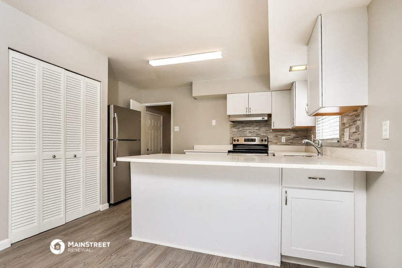 a white kitchen with white cabinets and a stainless steel refrigerator