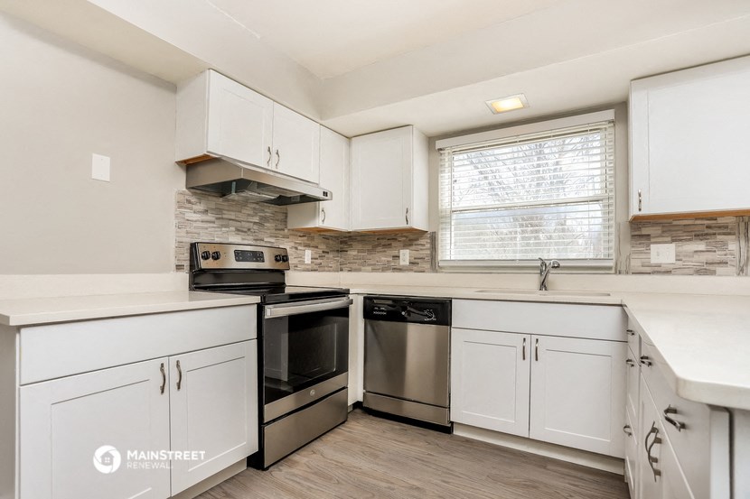 a kitchen with white cabinets and stainless steel appliances and a window