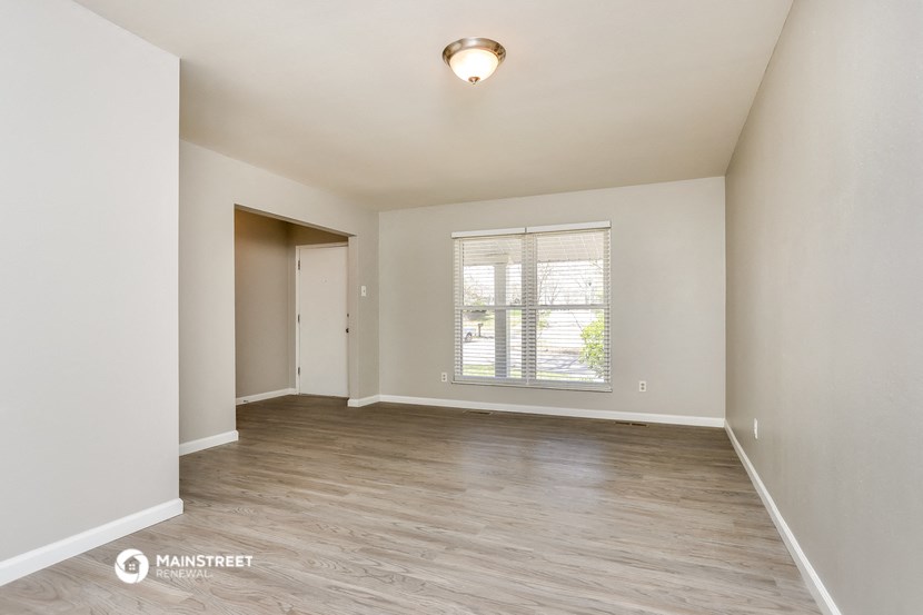 the spacious living room with a large window and wood flooring