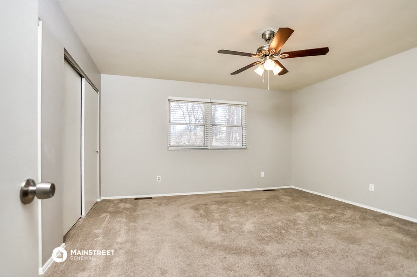 the spacious living room with carpet and a ceiling fan