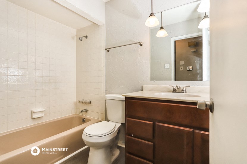 a bathroom with a toilet sink and tub and a mirror
