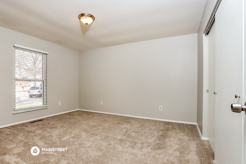the spacious living room with a large window and carpeted flooring