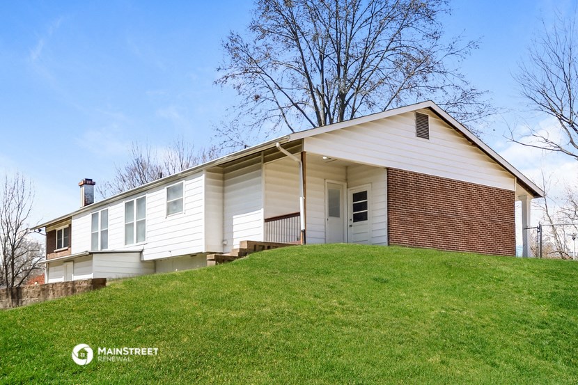 a white and brick house on top of a hill