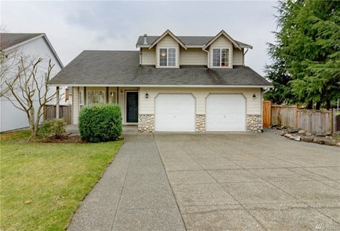 a white house with two white garage doors and a driveway