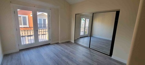 an empty living room with a mirror and a door to a balcony