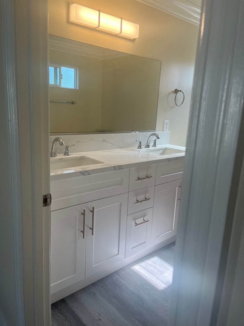 a white bathroom with two sinks and a mirror