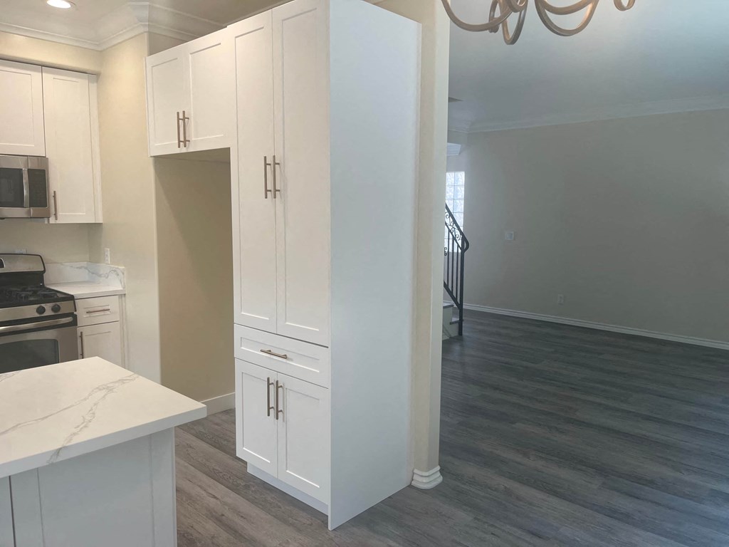 a renovated kitchen and living room with white cabinets