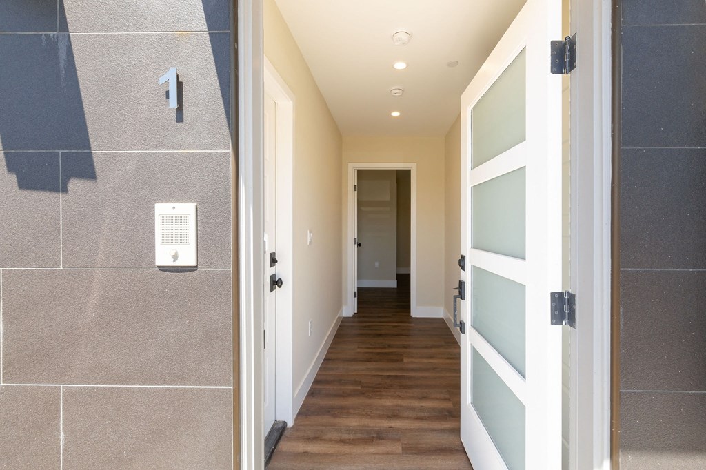 a hallway with a door to a bathroom and a hallway leading to a hall way