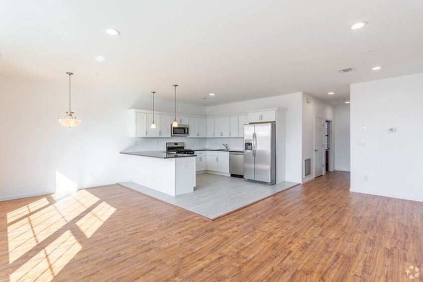 an empty kitchen and living room with a refrigerator and