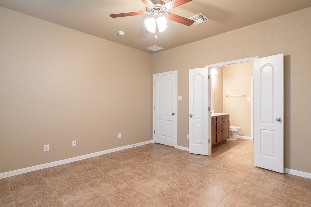 a empty living room with a ceiling fan and a bathroom