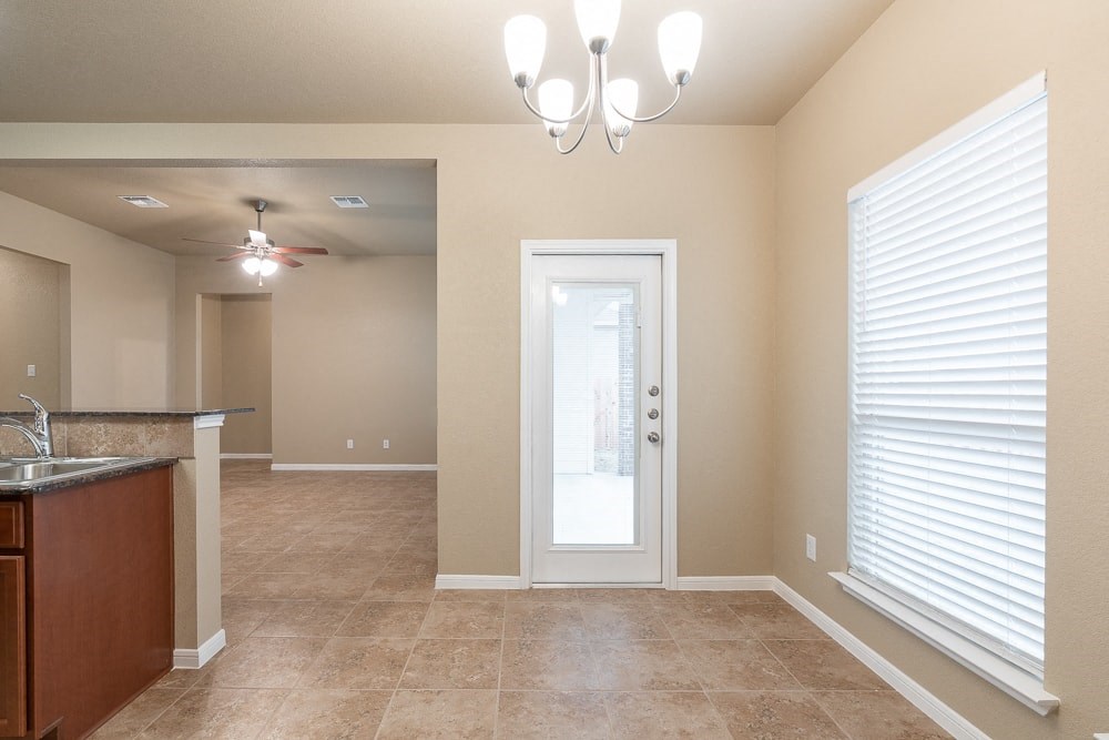 an empty living room with a white door and a kitchen