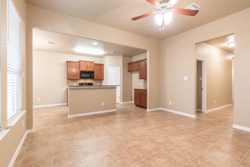 an empty living room and kitchen with a ceiling fan