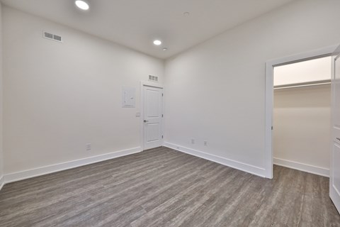 an empty living room with white walls and a door to a closet