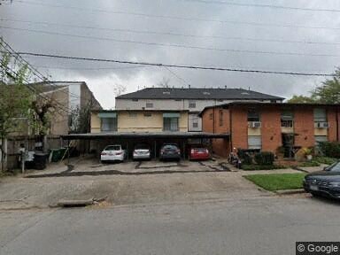 A cloudy day in a residential area with houses and cars.
