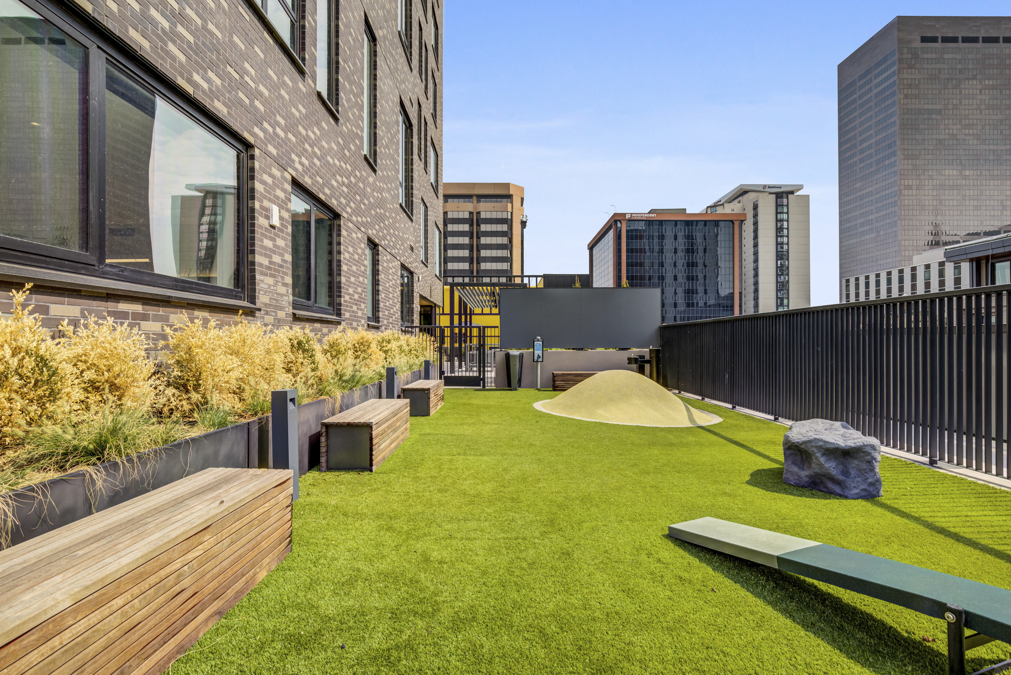 a grassy area with benches and a hill on a