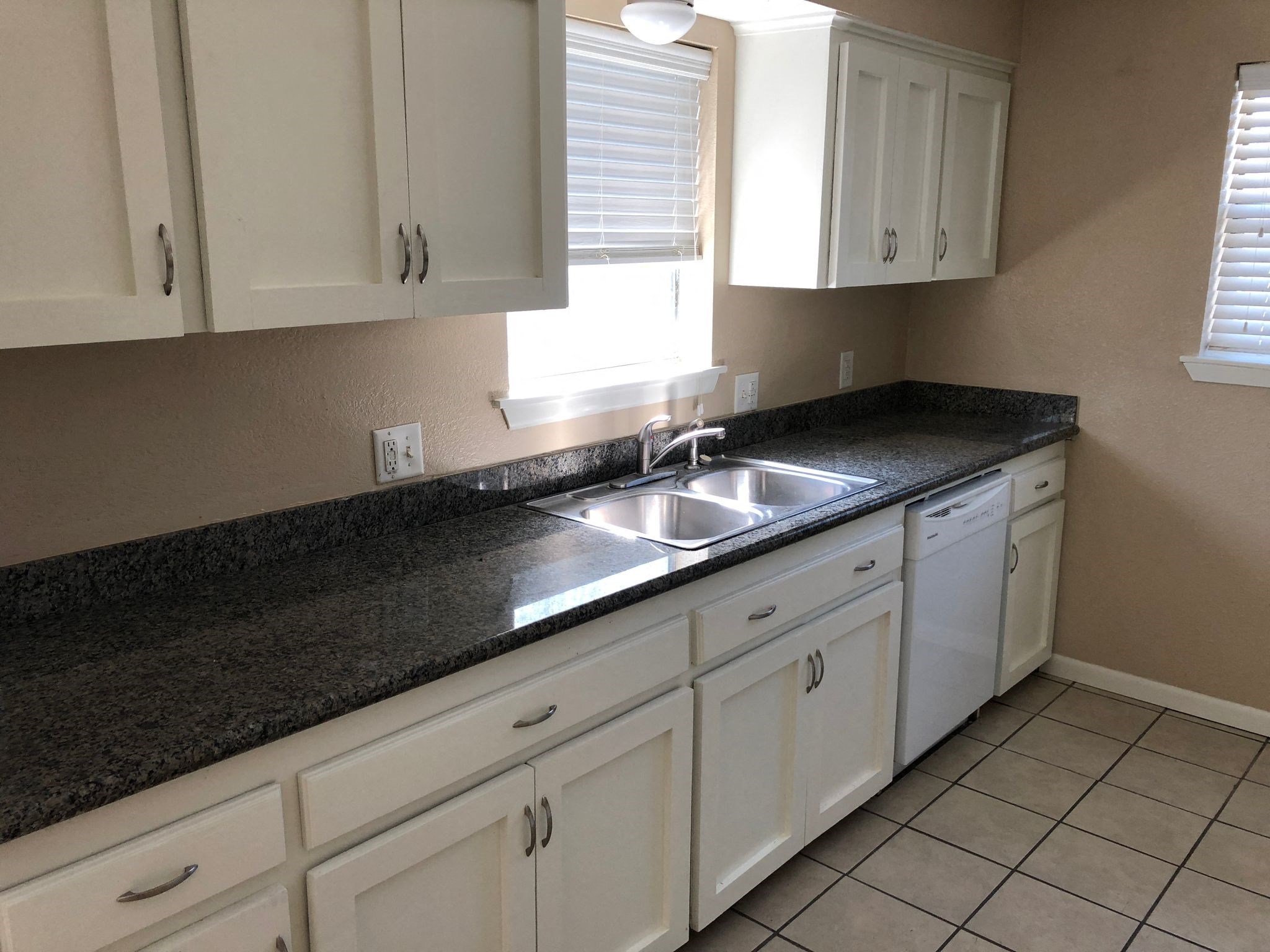 A kitchen with white cabinets and a black countertop.