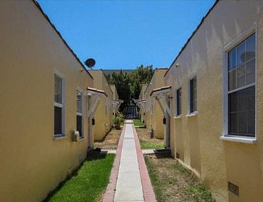 A narrow pathway leads between two rows of identical houses.