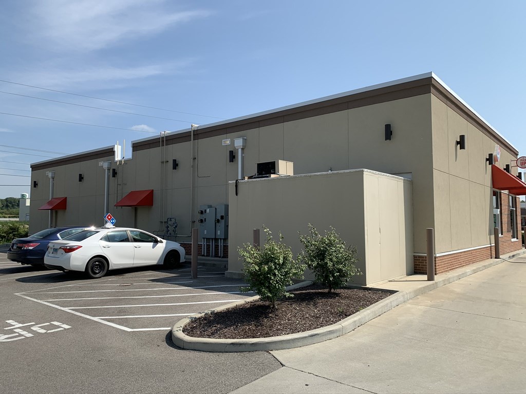 a tan building with cars parked in a parking lot