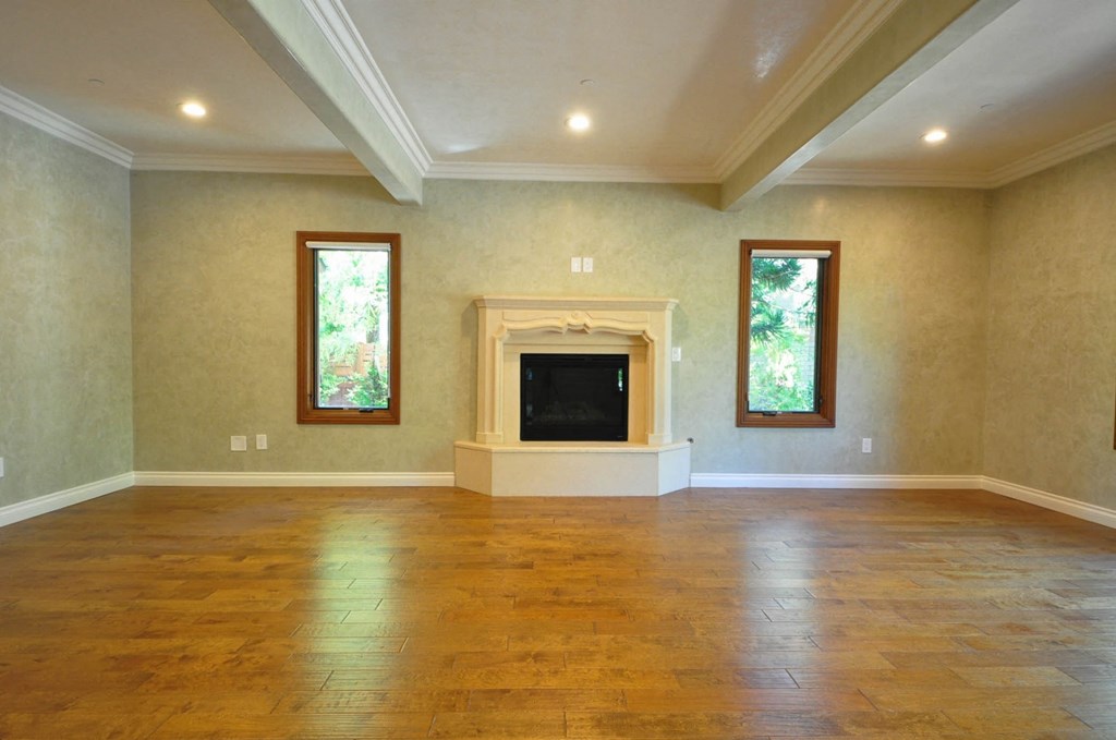 A spacious living room with a fireplace and two windows.