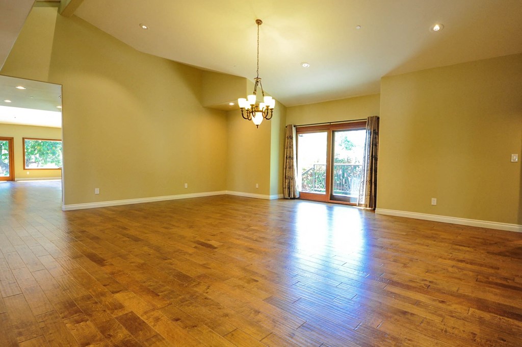 A large empty room with wooden floors and a chandelier.